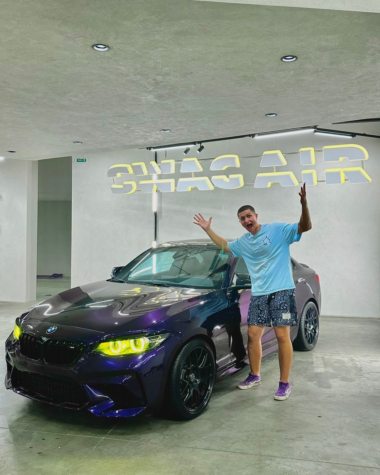 Витя рядом с BMW M2 в фиолетовой плёнке с жёлтыми фарами